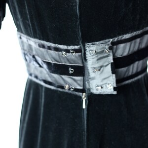 May include: Black velvet dress with a zip fastening and a black satin waistband with a row of buttons.