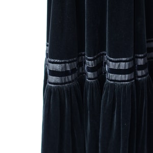 May include: A black velvet maxi skirt with a tiered design and black satin ribbon trim.