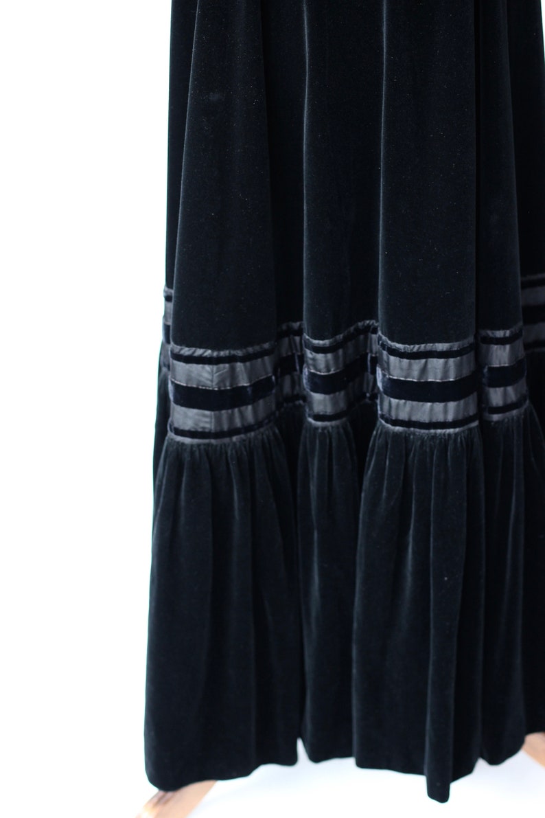 May include: A black velvet maxi skirt with a tiered design and black satin ribbon trim.