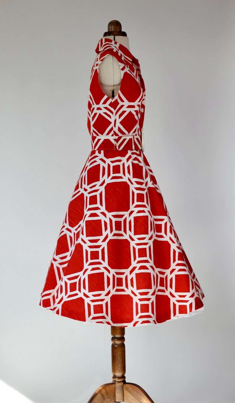 May include: A red and white geometric print dress with a fitted bodice and a full skirt. The dress has a collar and short sleeves.