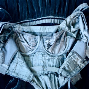 May include: A dark blue velvet dress with a built-in bra and a zip closure. The dress is open to reveal the bra and the lining of the dress.