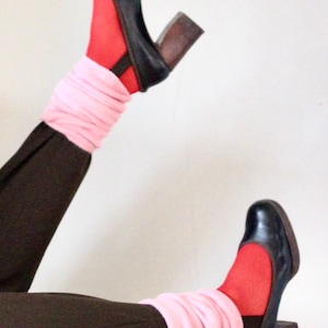 May include: A pair of black heeled shoes with a chunky heel. The shoes are worn with pink socks and red tights.