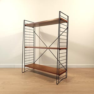 May include: A three-tier shelving unit featuring three horizontal wooden shelves supported by a black metal wire frame. The frame includes vertical ladder-like side supports and diagonal cross-bracing wires that connect the sides for stability.