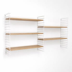 Peut inclure: Étagère murale modulaire avec une structure en métal blanc et des étagères en bois naturel. L'unité se compose de plusieurs sections, offrant des options de rangement polyvalentes. Les étagères sont rectangulaires.