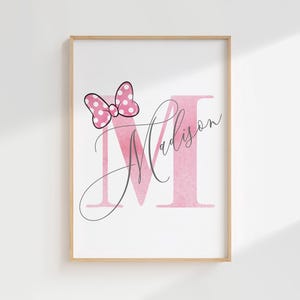 Puede incluir: Impresi&oacute;n enmarcada con una letra 'M' rosa y el nombre 'Madison' en cursiva. Un lazo rosa con lunares blancos est&aacute; encima de la letra. La impresi&oacute;n est&aacute; sobre un fondo blanco.
