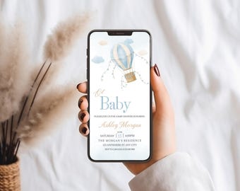 May include: A blue and white hot air balloon with gold accents and a string of white lights. The text "Oh Baby" is in blue and the text "Please join us for a baby shower honoring Ashley Morgan" is in black. The date and time of the event are listed as "Saturday June 15 4:00PM". The location is listed as "The Morgan's Residence 123 Anywhere St. Any City".