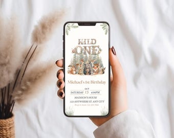 May include: A digital invitation for a first birthday party with a woodland theme. The invitation features a brown wooden sign with the text "Wild One" and a group of woodland animals including a fox, a bear, a squirrel, and a deer. The invitation also includes the date, time, and location of the party.