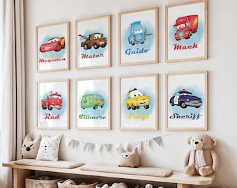 May include: Nine framed watercolor prints of Cars characters, including Lightning McQueen, Mater, and Guido, are displayed on a white wall. Each print features a car with its name in a colorful font. The prints are in light wood frames.