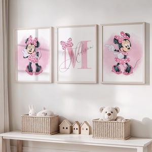 Könnte beinhalten: Drei gerahmte Minnie Mouse-Drucke in einem Kinderzimmer. Jeder Druck zeigt Minnie in einem rosa gepunkteten Kleid und einer Schleife, vor einem rosa Aquarellhintergrund. Der mittlere Druck enthält den Namen "Madison".