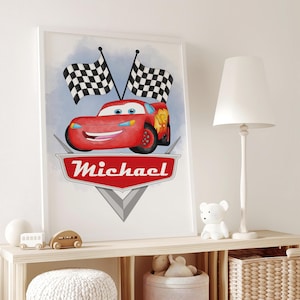 Puede incluir: Una impresión enmarcada con un coche de carreras rojo de dibujos animados con una cara sonriente, banderas a cuadros y el nombre "Michael" en un emblema rojo. El fondo tiene un efecto acuarela azul claro. La impresión se exhibe en una estantería de madera.