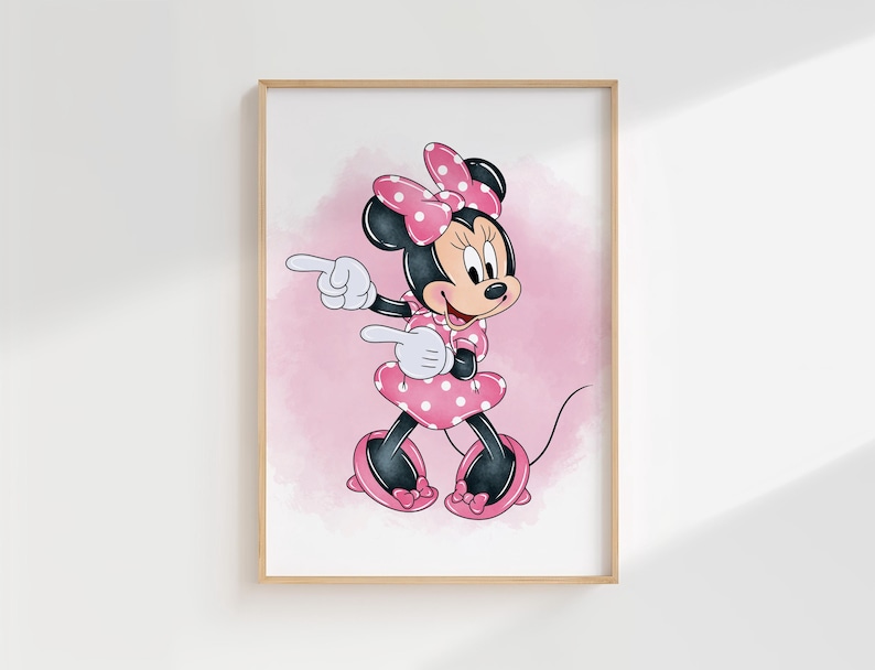 Puede incluir: Una impresi&oacute;n enmarcada con Minnie Mouse con un vestido y lazo de lunares rosas. El personaje de dibujos animados est&aacute; se&ntilde;alando con ambas manos sobre un fondo rosa de acuarela. La obra de arte est&aacute; en un marco de madera.