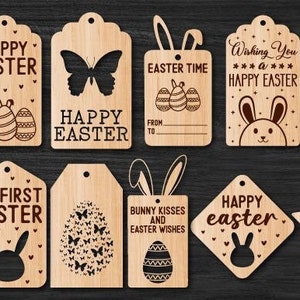May include: A collection of wooden Easter-themed tags with various designs. Some tags feature the text "Happy Easter," "Easter Time," and "My First Easter." Designs include Easter eggs, bunnies, butterflies, and stars. The tags are made of light-colored wood.