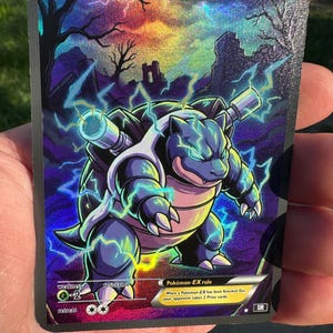 May include: A holographic Blastoise trading card featuring the character with two cannons on its back, surrounded by blue lightning. The card displays 600 HP, a grass weakness, and text including 'Basic', 'Blastoise', and 'Pokémon-EX rule'.