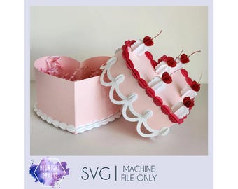Può includere: Una scatola rosa a forma di cuore con coperchio abbinato, decorata con bordi smerlati bianchi e accenti di ciliegie rosse. La scatola è aperta, rivelando un interno strutturato. L'immagine include il testo "SVG | MACHINE FILE ONLY".