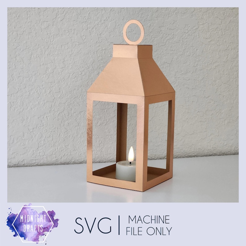 May include: A rose gold metal lantern with a candle inside. The lantern is made of paper and has a simple design. It is a decorative item for the home.