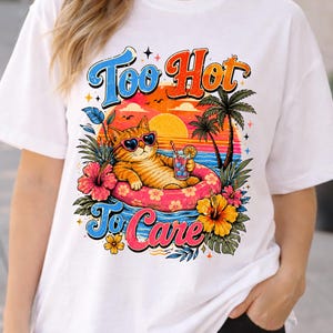 Peut inclure: T-shirt blanc avec un motif graphique. Il représente un chat tabby orange portant des lunettes de soleil en forme de cœur, se relaxant dans un anneau gonflable rose avec une boisson. Le motif comprend le texte "Too Hot To Care" avec un coucher de soleil tropical et des palmiers.