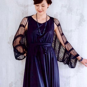 May include: A woman wearing a navy blue dress with a black lace shawl. She is wearing a necklace with blue beads.