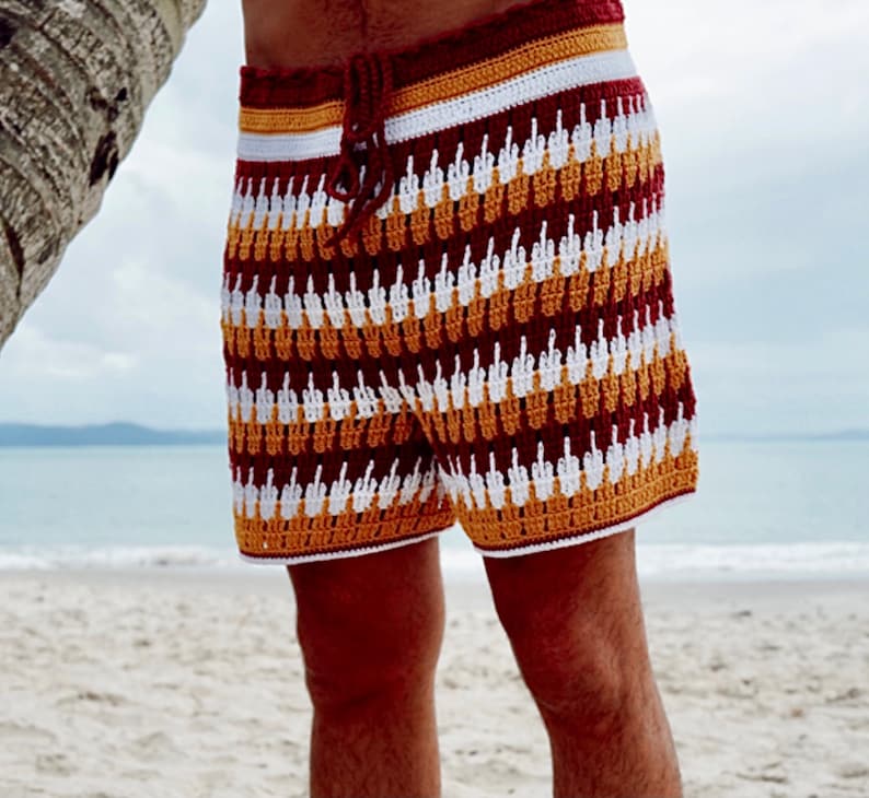 Pu&ograve; includere: Shorts a crochet rosso, bianco e giallo con un motivo di dita in rilievo. I pantaloncini hanno una vita con coulisse.