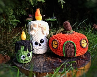 May include: Crocheted Halloween decorations including a green Frankenstein's monster candle, a white skull candle, and an orange pumpkin house with a brown door and yellow windows. The candles have yellow flames.