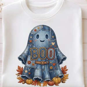 Peut inclure: Un sweat-shirt blanc à col rond avec un motif central représentant un fantôme fait de pièces de tissu en jean bleu. Le fantôme porte l'inscription BOO en lettres orange, une ceinture marron, entouré de feuilles d'automne et de citrouilles.