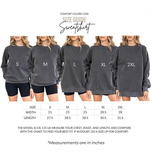 K&ouml;nnte beinhalten: Eine Gr&ouml;&szlig;entabelle f&uuml;r ein graues Comfort Colors 1566 Sweatshirt. Das Bild zeigt f&uuml;nf Sweatshirts in den Gr&ouml;&szlig;en S, M, L, XL und 2XL. Die Gr&ouml;&szlig;entabelle enth&auml;lt Breiten- und L&auml;ngenma&szlig;e in Zoll. Das Model ist 172.7 cm, 56.7 kg.