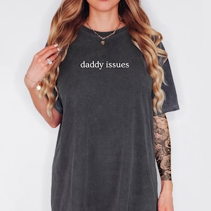 May include: A dark gray oversized t-shirt with the text "daddy issues" printed in white on the front.