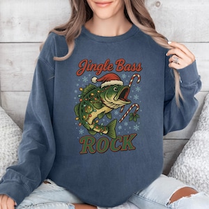 Pu&ograve; includere: Felpa blu navy con grafica a tema natalizio. Il design presenta un pesce con un cappello da Babbo Natale e luci natalizie, con le parole "Jingle Bass Rock" in rosso e verde.