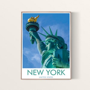 May include: A framed poster featuring the Statue of Liberty against a blue sky. The statue is green with a gold torch. The poster has the words "NEW YORK" and "UNITED STATES" in white text at the bottom.