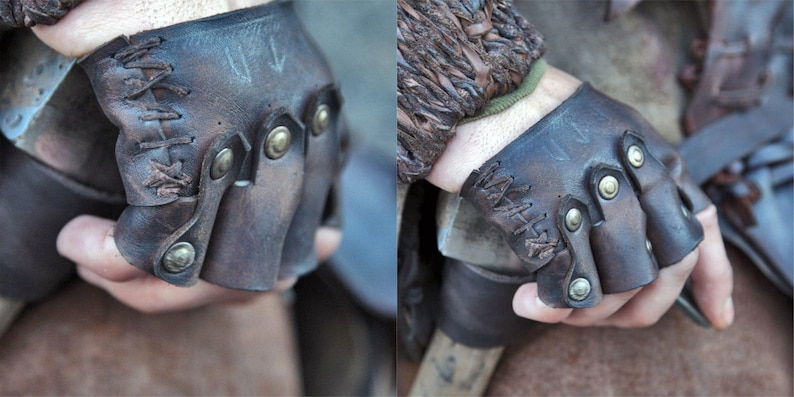 May include: A pair of fingerless dark brown leather gloves featuring a distressed finish, decorative cross-stitching along the side, and metallic brass-toned studs securing the individual finger sections across the knuckles for a structured fit.