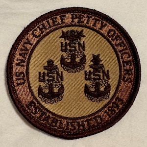 May include: A brown and tan embroidered patch with the text "US Navy Chief Petty Officers Established 1893" in a circle around three anchors with the text "USN" on each.