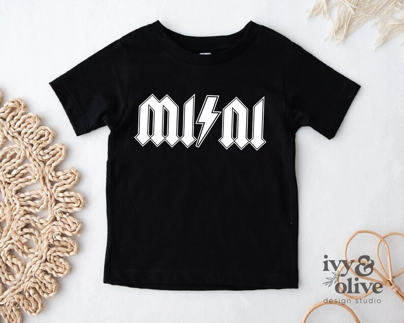 Puede incluir: Camiseta negra con texto blanco que dice "MUSH" con un rayo en el medio.