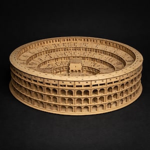 Könnte beinhalten: Ein kreisförmiges Holzmodell des Kolosseums mit mehreren Ebenen von Bogenöffnungen und einer detaillierten Innenstruktur der Arena. Das hellbraune Material zeigt komplizierte lasergeschnittene Muster, die das architektonische Design nachbilden.