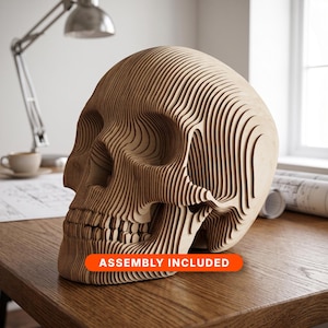 Peut inclure: Une sculpture de crâne en bois brun clair construite à partir de multiples couches empilées découpées au laser, créant une texture nervurée topographique. L'objet présente une étiquette rectangulaire orange avec le texte ASSEMBLY INCLUDED.