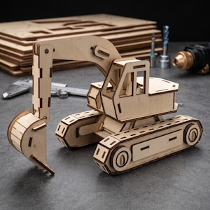 May include: A light-colored wooden model of an excavator featuring a movable boom, a bucket, and tracked undercarriage. The construction toy is assembled from laser-cut plywood pieces with visible interlocking joints and a detailed cabin structure.