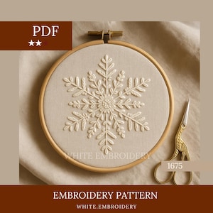 Puede incluir: Patrón de bordado de copo de nieve blanco sobre tela beige, en un aro de madera. Unas tijeras doradas están colocadas al lado. El texto "WHITE EMBROIDERY" y "EMBROIDERY PATTERN" son visibles.