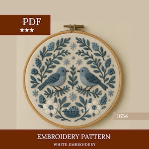 Puede incluir: Un bastidor de bordado con un diseño detallado de dos pájaros azules posados en ramas, rodeados de elementos florales azules y blancos. El texto "EMBROIDERY PATTERN" y "WHITE.EMBROIDERY" son visibles. El icono PDF está en la esquina superior izquierda.