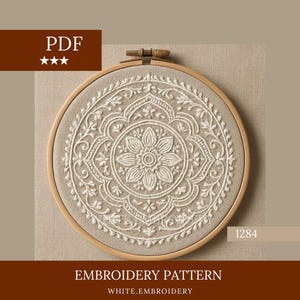 以下が含まれることがあります： ベージュ色の生地に白い花の模様が施された、円形の刺繍パターン。木製の刺繍枠に収められています。「PDF」と「EMBROIDERY PATTERN」の文字が含まれています。パターンには番号「1284」が記載されています。