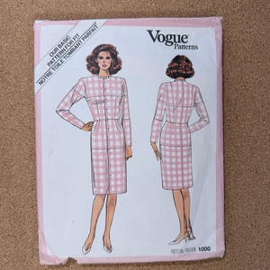 May include: A Vogue Patterns sewing pattern envelope featuring a pink and white gingham dress design. The envelope includes text in English and French, and the pattern number is 1000.