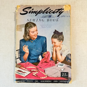 May include: A vintage Simplicity Sewing Book with a blue cover featuring an illustration of a person in a blue shirt sewing with a needle and thread, alongside a child. The cover includes the text Simplicity SEWING BOOK and a price of 25 cents.