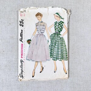 May include: Vintage Simplicity pattern envelope featuring illustrations of two dresses. One dress is a light pink with a sheer bodice, and the other is a green and white plaid. The envelope has text that reads "Size 16 Bust 34" and "Printed Pattern 25c".