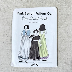 May include: A vintage sewing pattern titled "Park Bench Pattern Co. Elm Street Park Pattern No. 1." The cover features three illustrated figures wearing dresses. The illustration is in black and white with accents of blue and yellow.