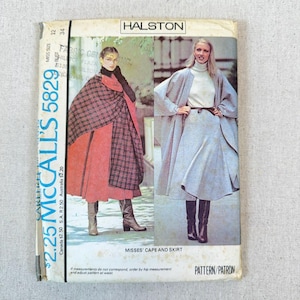 May include: A vintage Halston McCall's 5829 sewing pattern envelope for a misses' cape and skirt. The front features two illustrations of the garments: one in a red and black plaid cape over a red skirt, and one in a light gray cape and skirt set.