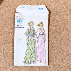 May include: A vintage Vogue Pattern envelope featuring illustrations of two women in flowing dresses. The envelope is white with the number 7950 and the Vogue Pattern logo. The illustrations depict a floral robe and a pink gown.