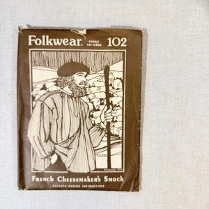 May include: A brown paper pattern titled "Folkwear Ethnic Patterns 102" featuring a black and white illustration of a man in a French Cheesemaker's Smock. The pattern includes sewing instructions.