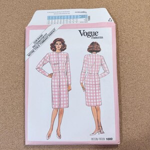 May include: A pink and white gingham dress pattern from Vogue Patterns. The pattern envelope features illustrations of the dress design, with text that reads "OUR BASIC PATTERN FOR FIT" and "PATTERN/PATRON 1000".
