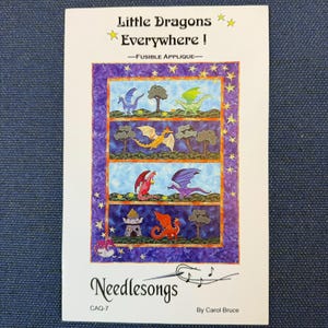 May include: A white instructional booklet titled Little Dragons Everywhere! Fusible Applique by Carol Bruce. The cover features a rectangular illustration divided into four horizontal panels, each depicting colorful dragons, trees, and a stone tower.