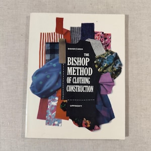 May include: A book titled "The Bishop Method of Clothing Construction" with a white cover. The cover features fabric swatches in various colors and patterns, including red stripes, blue polka dots, and floral prints. The book is published by Lippincott.