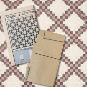 May include: Two vintage Vogue pattern books are displayed on a patterned background. One book is open, revealing a black and white geometric design. The other book is closed, with a tan cover. The background features a repeating pattern of white, pink, and gray squares.