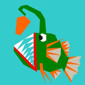 Puede incluir: Un pez pescador verde con una boca grande y dientes afilados, sosteniendo un pequeño señuelo naranja. El pez tiene un ojo blanco y aletas naranja y grises.