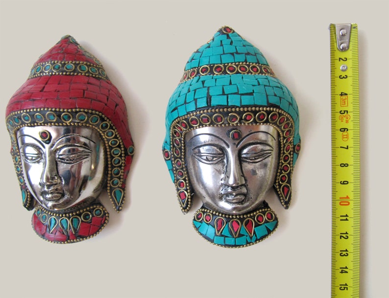Op de afbeelding: Twee zilveren Boeddha-wanddecoraties met turquoise en rode moza&iuml;ektegels. De Boeddha-gezichten zijn zilver met een gouden rand. De Boeddha links heeft rode moza&iuml;ektegels en de Boeddha rechts heeft turquoise moza&iuml;ektegels.